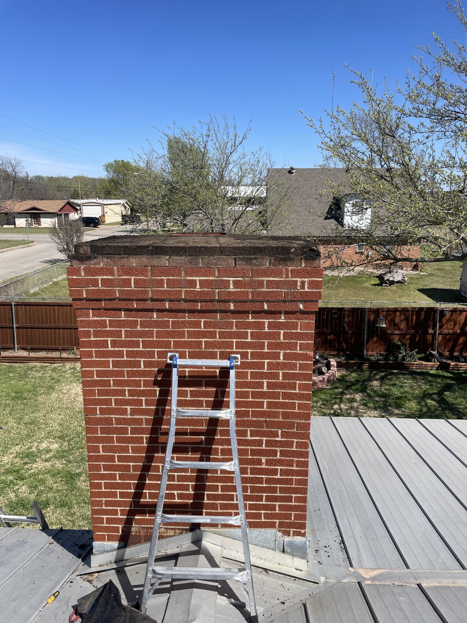 Chimney during service with the old cap removed, exposing the worn brick crown and open flue opening