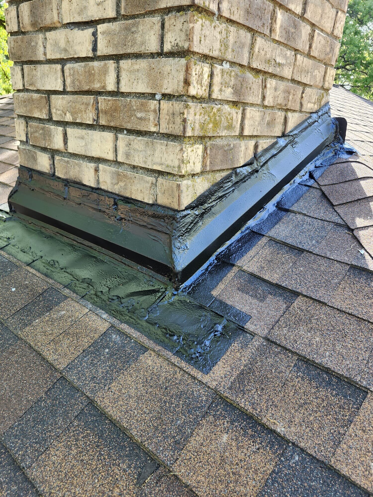 Completed chimney flashing along the corner of the brick chimney with sealed counter flashing over the shingles