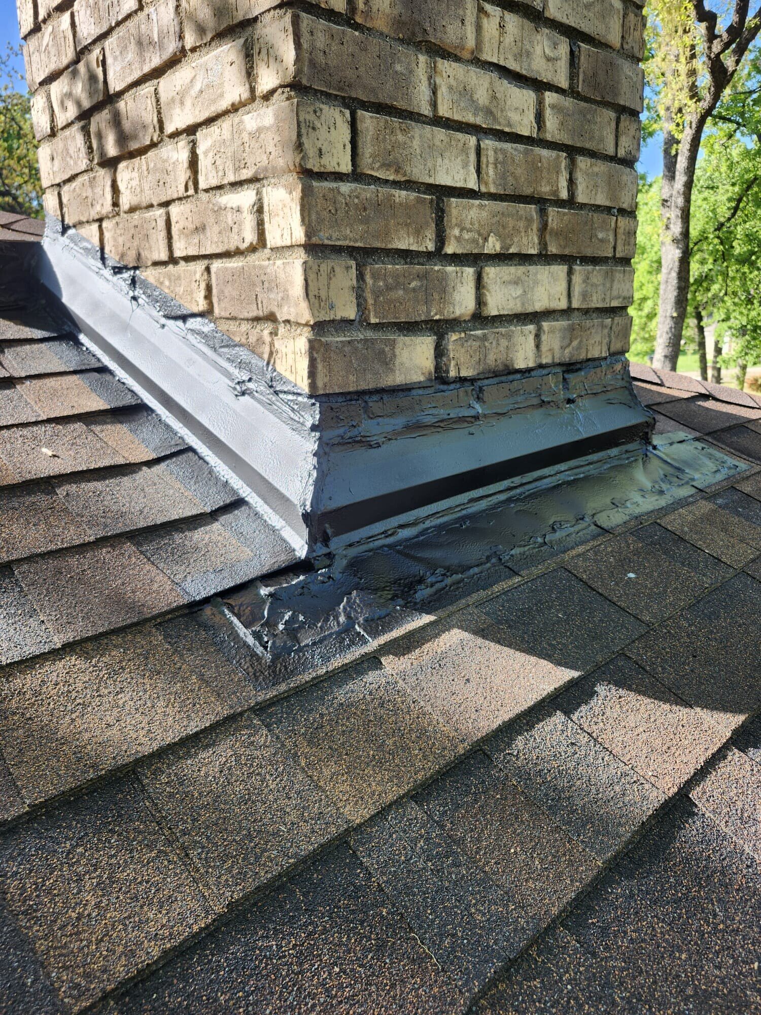 Side view of the completed chimney flashing showing the sealed step and base flashing where the chimney meets the roof