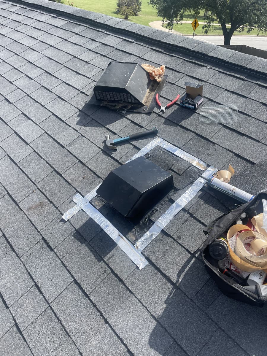 Rooftop dryer vent replacement in progress, with the old vent cap removed and tools and vent components staged on the shingles